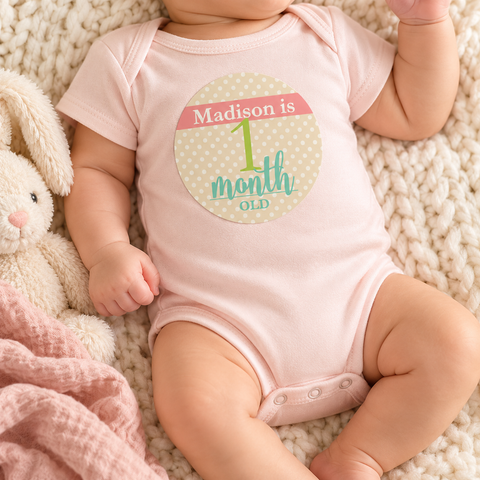 Baby girl's first month photo with a personalized monthly milestone sticker