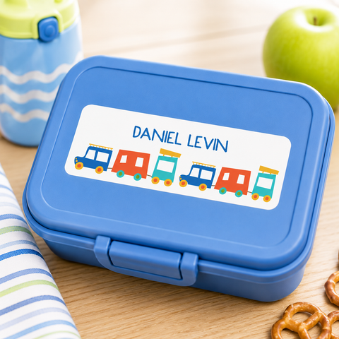 Blue sandwich container with personalized train name label for kids, styled with matching lunch accessories in a bright modern school lunch setup.